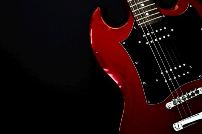 Red electric guitar closeup isolated on black background